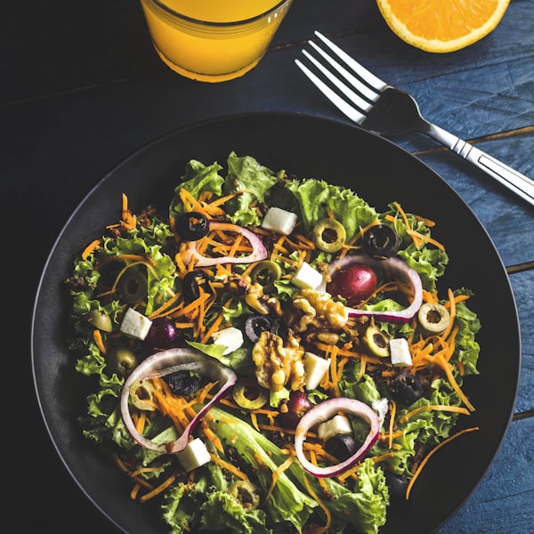 A colorful plated salad with greens, feta, olives and walnuts, showing ingredients a cook might recognize from a dish photo